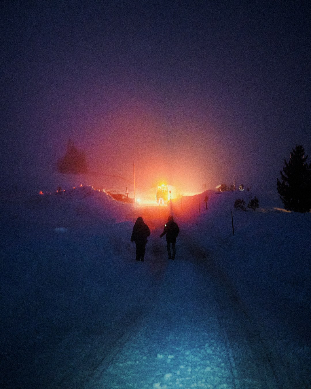 Winter crew silhouetted against a warm light in the snow